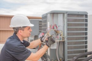 man looking at AC unit gauges
